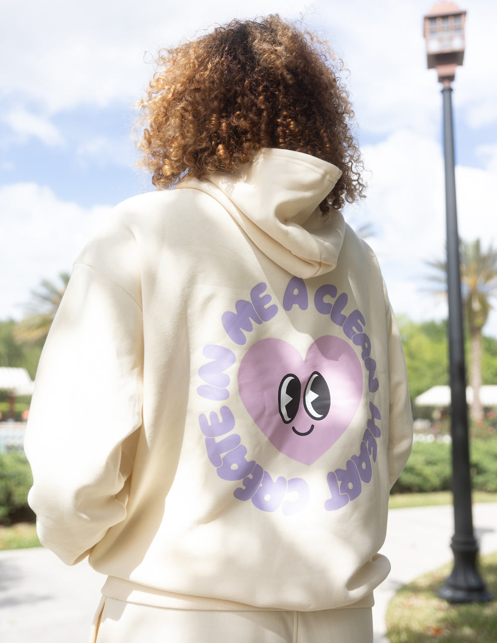 Elevated Faith Christian Hoodie in cream color with heart graphic and smiley face design on the back