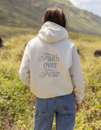 Elevated Faith Christian Hoodie with 'Faith over Fear' graphic on the back in a natural outdoor setting