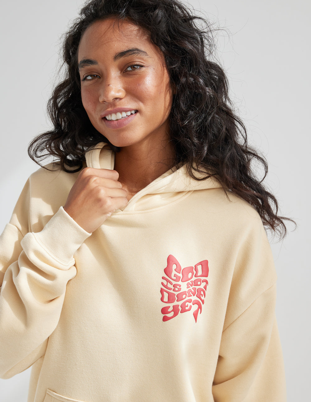 Cream Elevated Faith Christian Hoodie with 'God is not done yet' graphic on the front