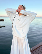 White Elevated Faith Christian Hoodie with a relaxed fit, perfect for casual wear by the water