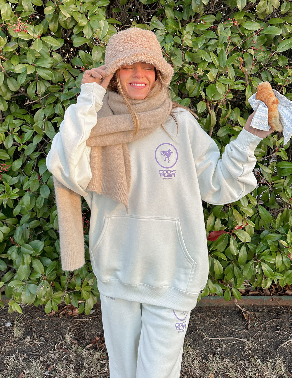 Woman wearing a cozy Elevated Faith Christian Hoodie in light color, styled with a scarf and hat