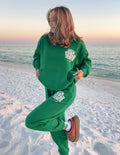 Green Elevated Faith Christian Hoodie with 'Out Kind of Jesus' Design on the Beach at Sunset