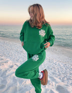 Green Elevated Faith Christian Hoodie with 'Out Kind of Jesus' Design on the Beach at Sunset
