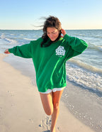 Green Christian Hoodie from Elevated Faith with 'Your Need is Jesus' graphic on beach