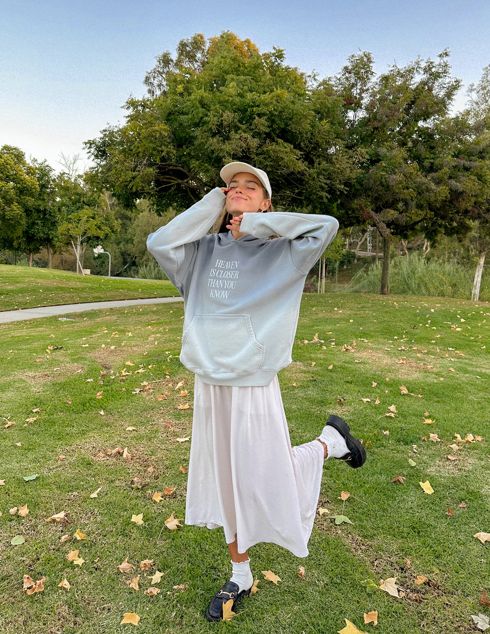 Model wearing a light blue Christian Hoodie in a natural setting with a joyful expression