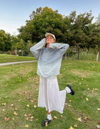 Model wearing a light blue Christian Hoodie in a natural setting with a joyful expression