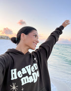 Woman wearing Elevated Faith Christian Hoodie with 'Heaven Made' graphic at sunset by the beach