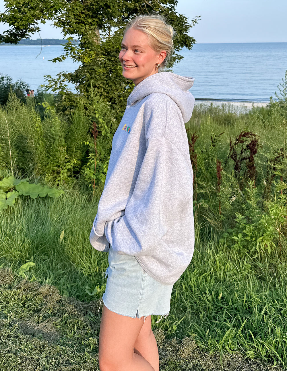 Light gray Elevated Faith Christian Hoodie styled with a casual summer outfit by the beach