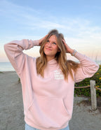 Elevated Faith Christian Hoodie in Light Pink with 'His Love Endures Forever' Design at the Beach