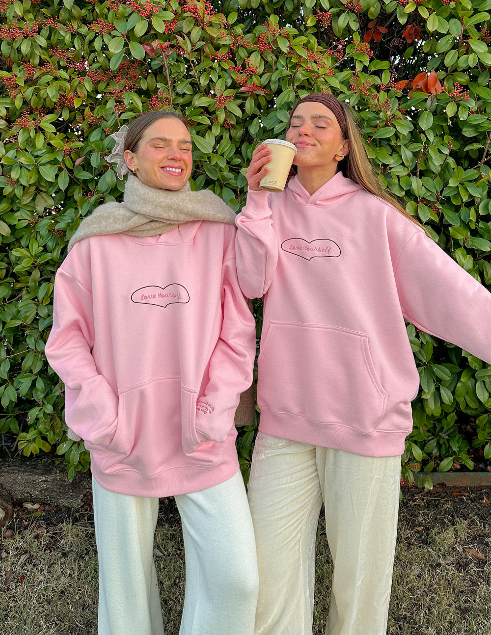 Two models wearing soft pink Elevated Faith Christian Hoodies with matching relaxed bottoms outdoors