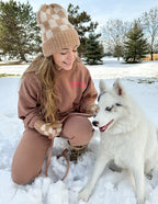 Woman wearing a cozy Elevated Faith Christian Hoodie in snow with a pet dog, enjoying winter outdoors