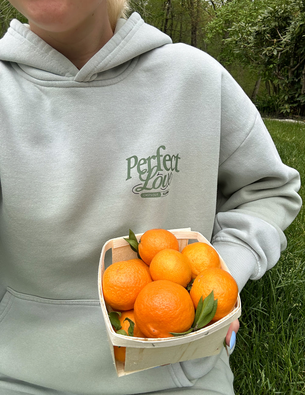 Light gray Christian Hoodie by Elevated Faith with 'Perfect Love' graphic and oranges in a basket