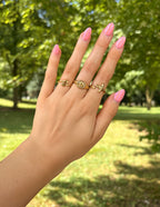 Elevated Faith Christian Jewelry rings displayed on a hand with pink nails in a sunny outdoor setting