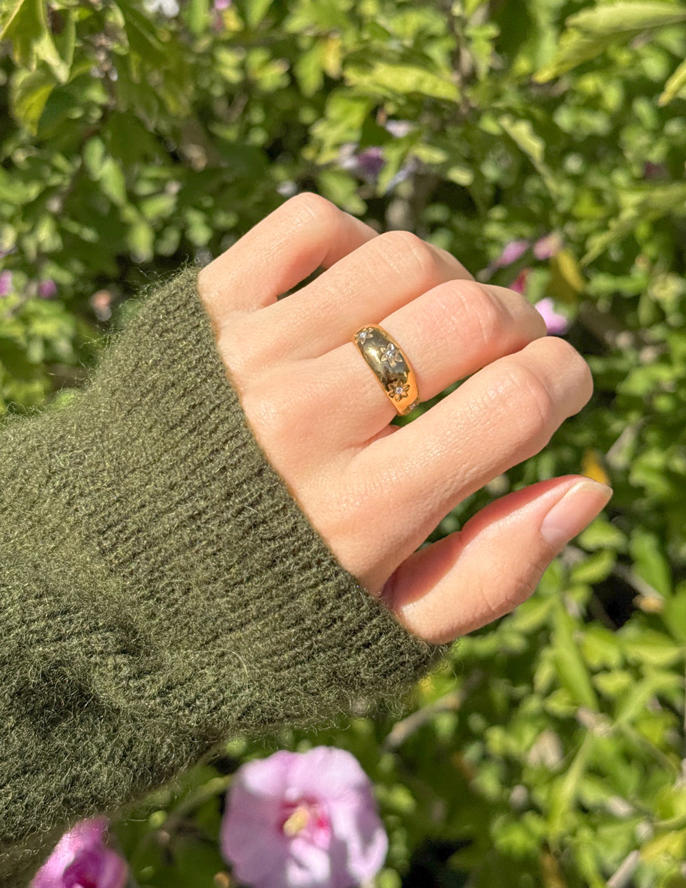 Elevated Faith Christian Jewelry Gold Ring on Hand Surrounded by Greenery and Flowers