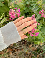 Gold heart design ring worn on a hand among vibrant pink flowers, perfect Christian Jewelry
