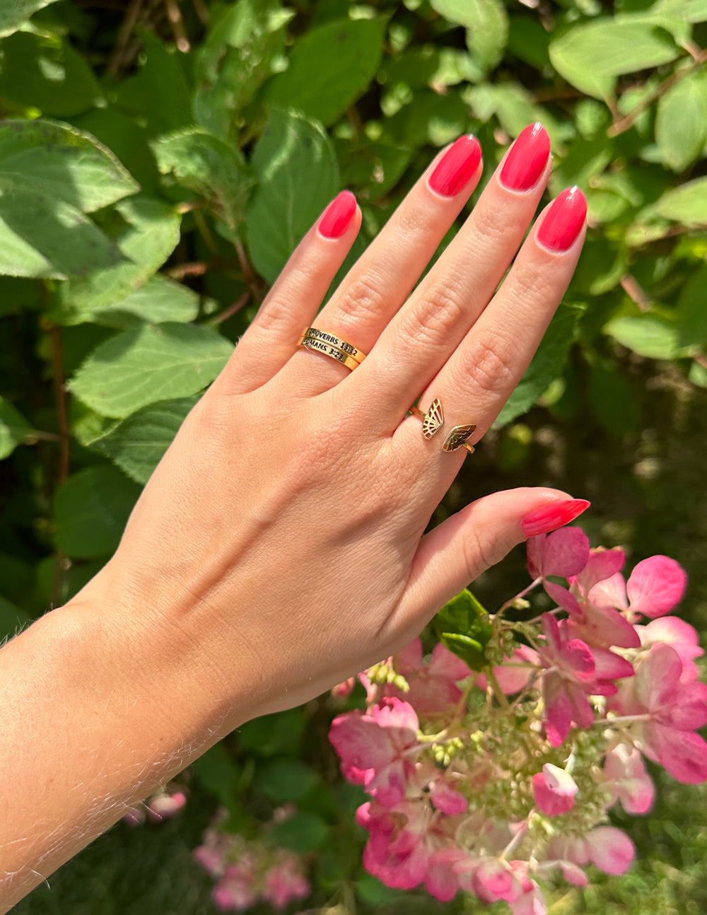 Elevated Faith Christian Jewelry Ring on hand with pink nails and flowers in the background