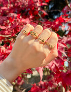 Gold Christian Jewelry rings featuring cross designs in a natural setting with vibrant red leaves
