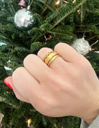 Elevated Faith Christian Jewelry Ring Stack with three gold bands on a hand against a festive background