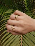 Gold Elevated Faith Ring with Christian Jewelry Design on a Hand Against a Green Leaf Background