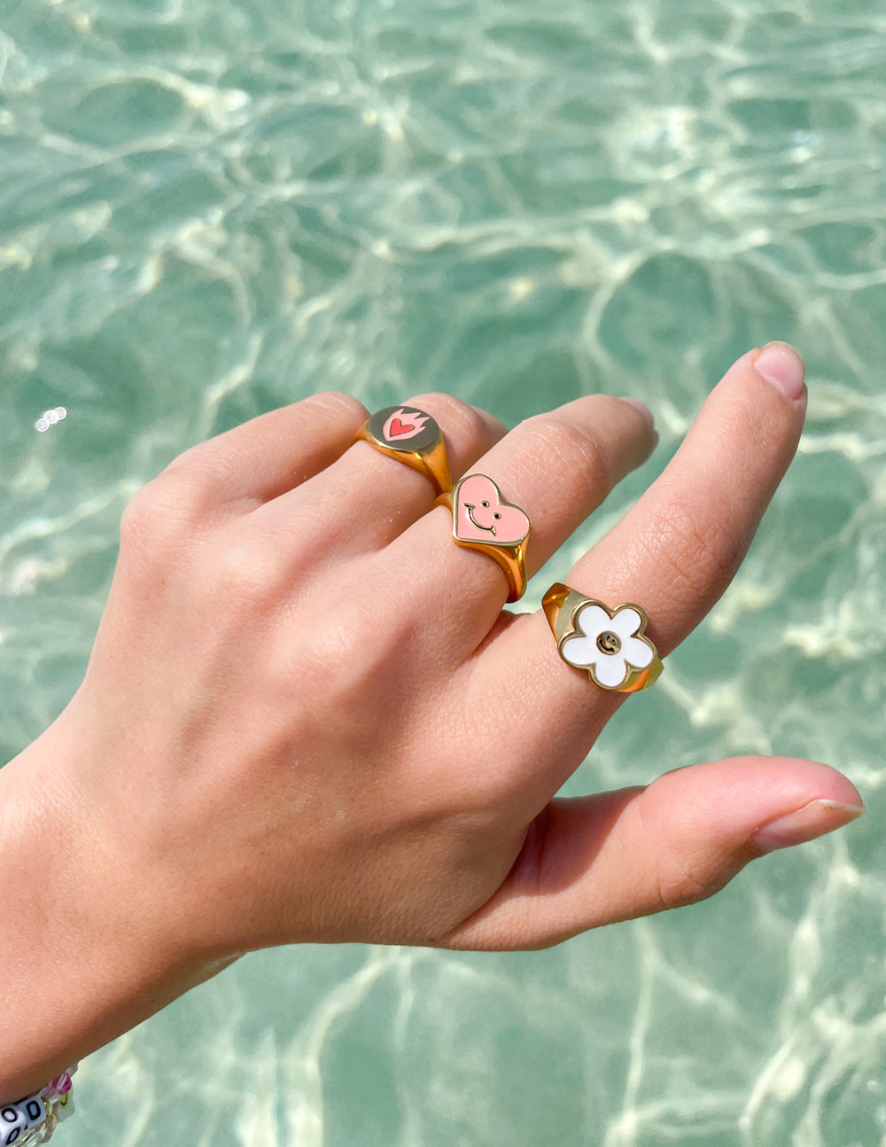 Elevated Faith Christian Jewelry featuring colorful, playful rings on a hand by the water