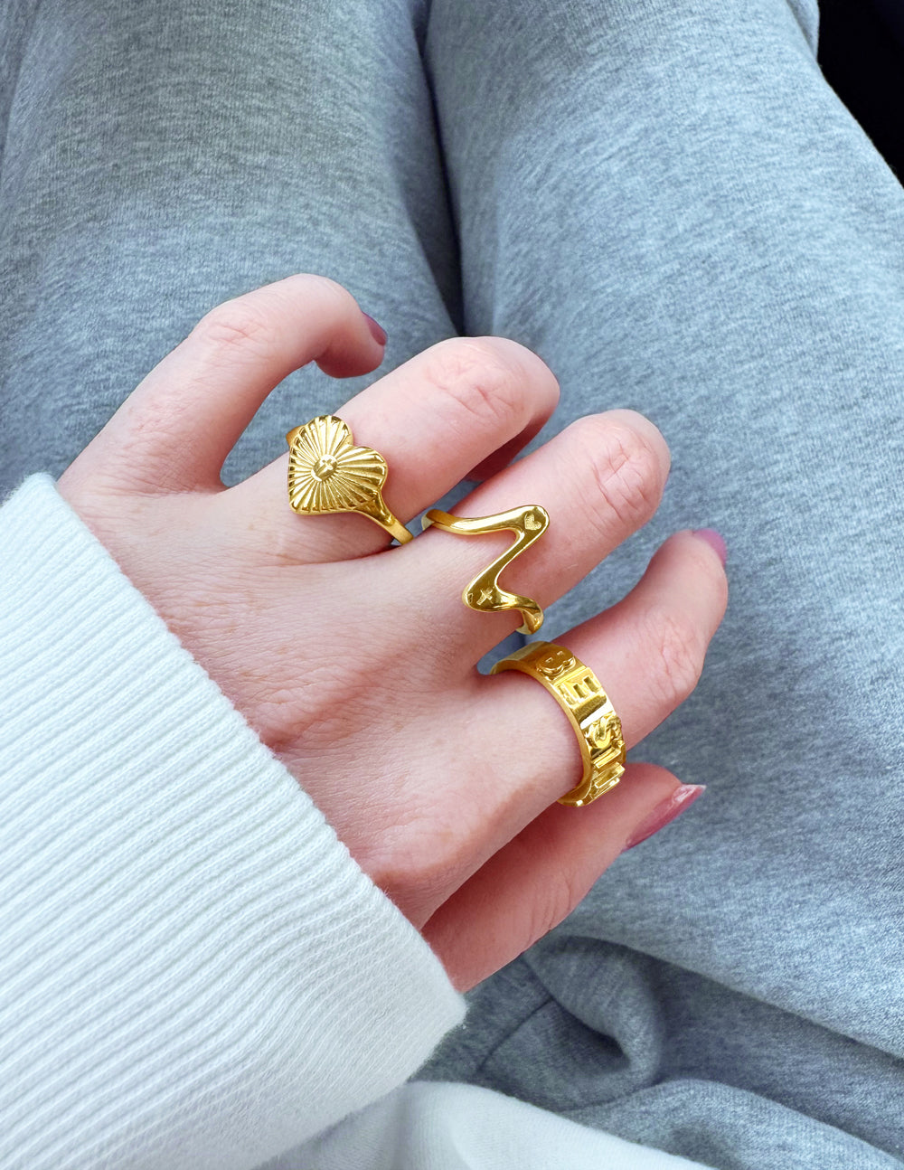 Gold rings displayed on a hand featuring unique designs, perfect for Christian Jewelry enthusiasts