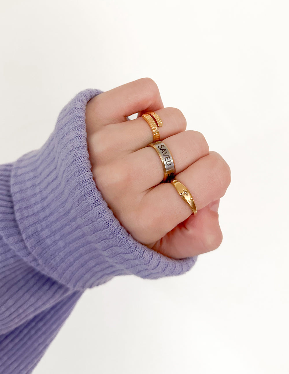 Three Elevated Faith Christian Jewelry rings worn on a hand with a lavender sweater sleeve