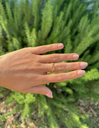 Elegant gold ring on a hand surrounded by greenery, showcasing Elevated Faith Christian Jewelry