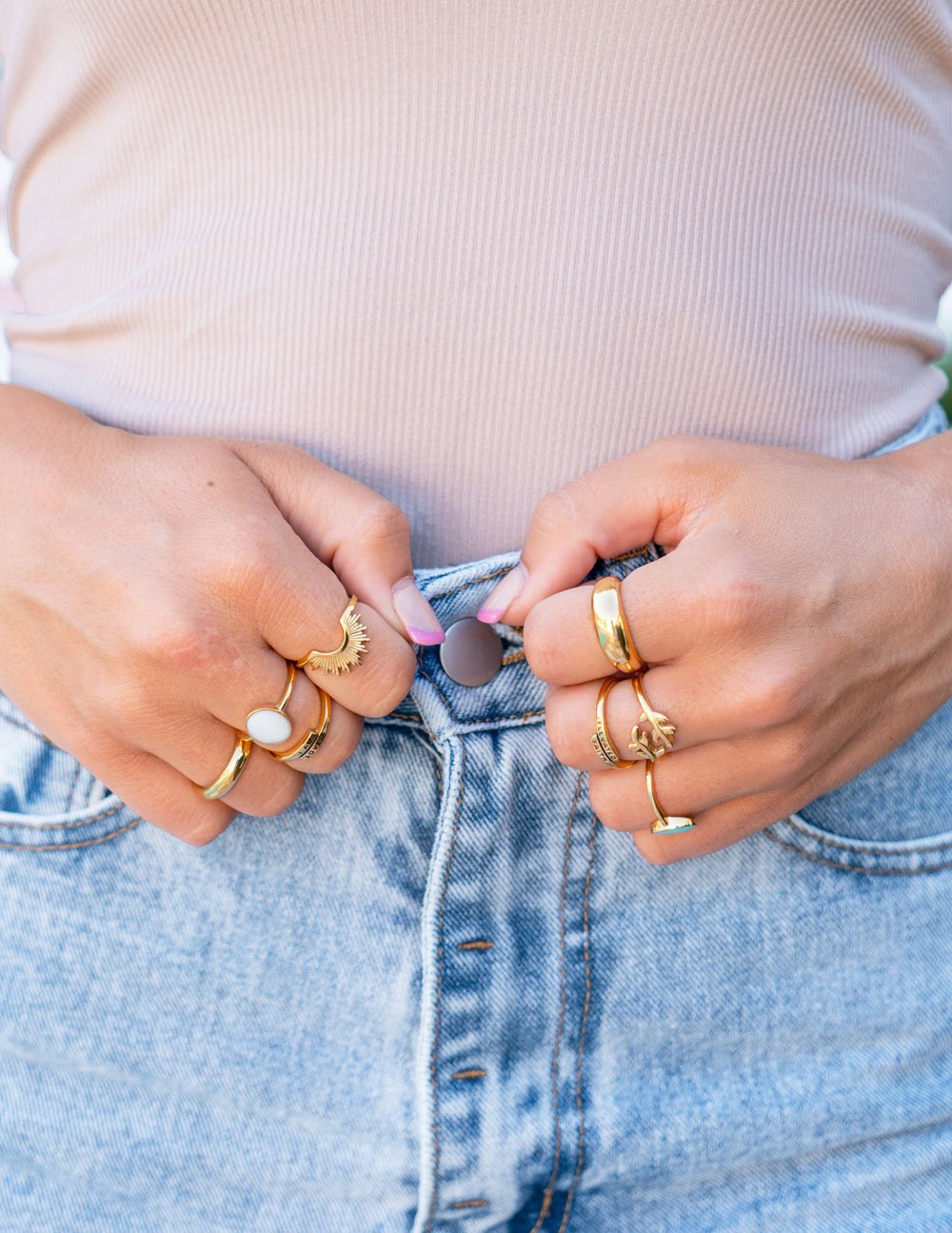Gold rings stacked on fingers, featuring sun and stone designs for Christian Jewelry lovers