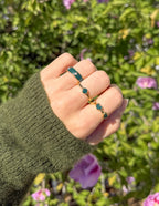 Elevated Faith Christian Jewelry featuring two stylish rings on a hand with a green sweater among flowers