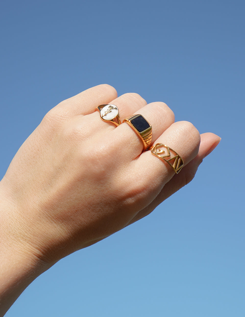 Gold Elevated Faith Christian Jewelry rings displayed on a hand against a clear blue sky