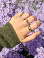 Elegant Elevated Faith Christian Jewelry featuring stacked rings on a hand among purple flowers