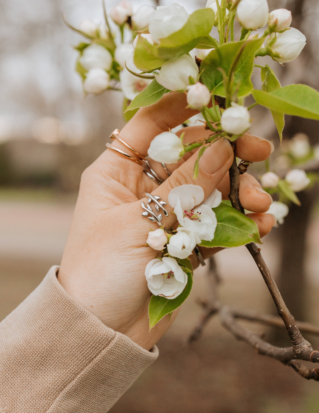 Hand holding flowers wearing Elevated Faith rings, showcasing elegant Christian jewelry