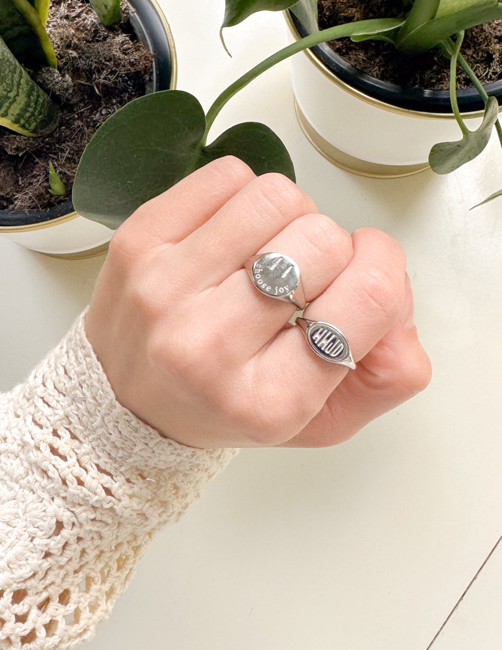 Elevated Faith Christian Jewelry featuring a stylish silver ring on a hand among potted plants