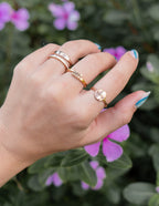 Elevated Faith Christian Jewelry rings displayed on a hand amidst blooming flowers