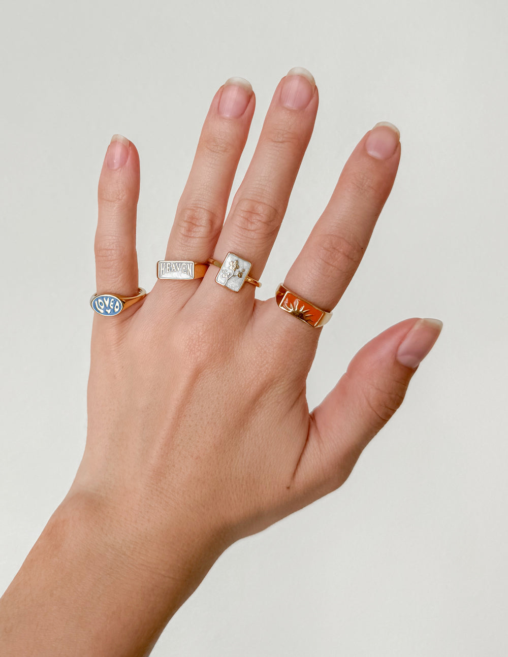 Five stylish rings on a hand, showcasing Elevated Faith's unique Christian Jewelry collection