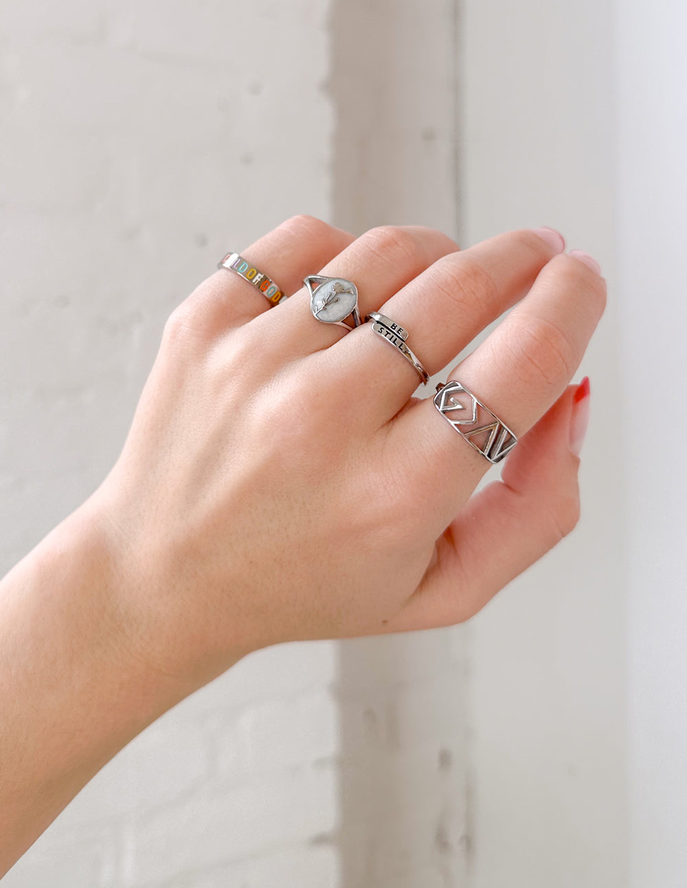 Silver rings with unique designs showcasing Christian Jewelry on a hand with manicured nails