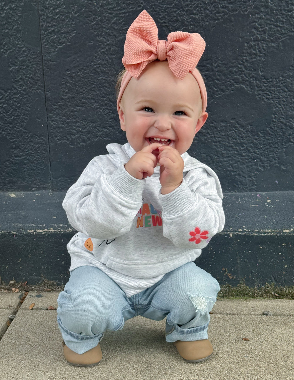 Cute toddler in a gray hoodie from Elevated Faith, featuring Christian Kids Apparel design and a large hair bow