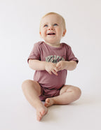 Cute toddler wearing a mauve onesie with a fun design from Elevated Faith, perfect Christian Kids Apparel