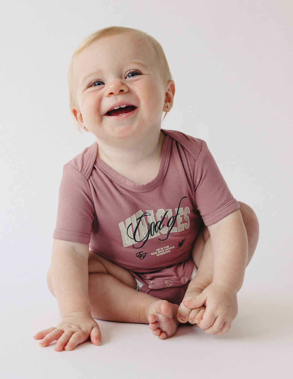 Adorable baby in a pink onesie with text, perfect for Christian Kids Apparel on casual days