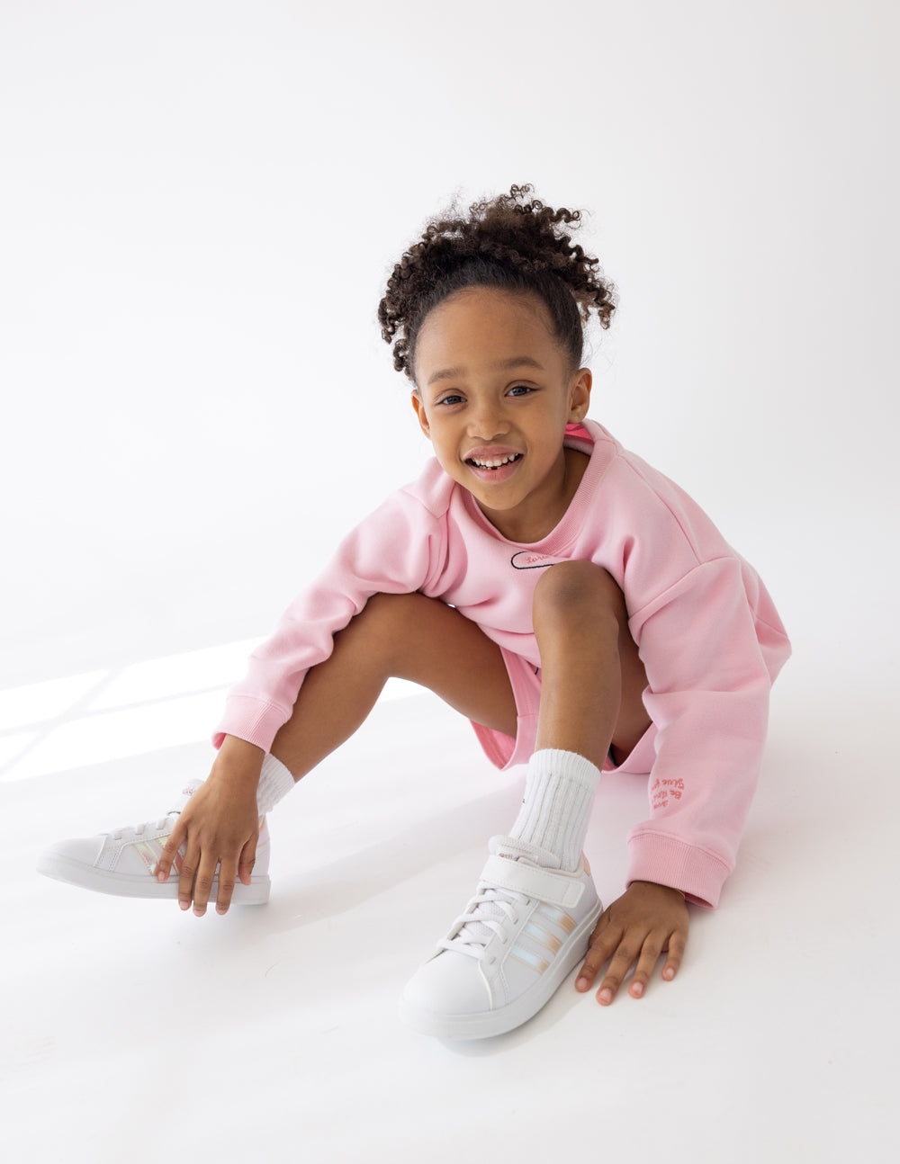 Cute girl in pink crewneck sweater from Elevated Faith showcasing Christian Kids Apparel style