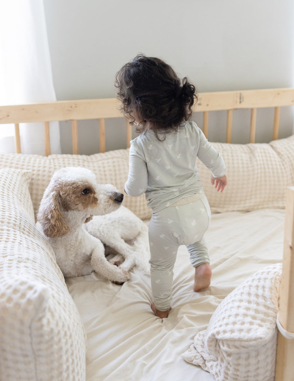 Toddler in Elevated Faith Kids Pajama playing in a crib with a dog, ideal for Christian Kids Apparel