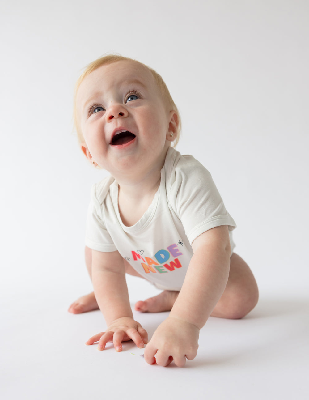 Baby crawling in Elevated Faith onesie that promotes Christian Kids Apparel with colorful design