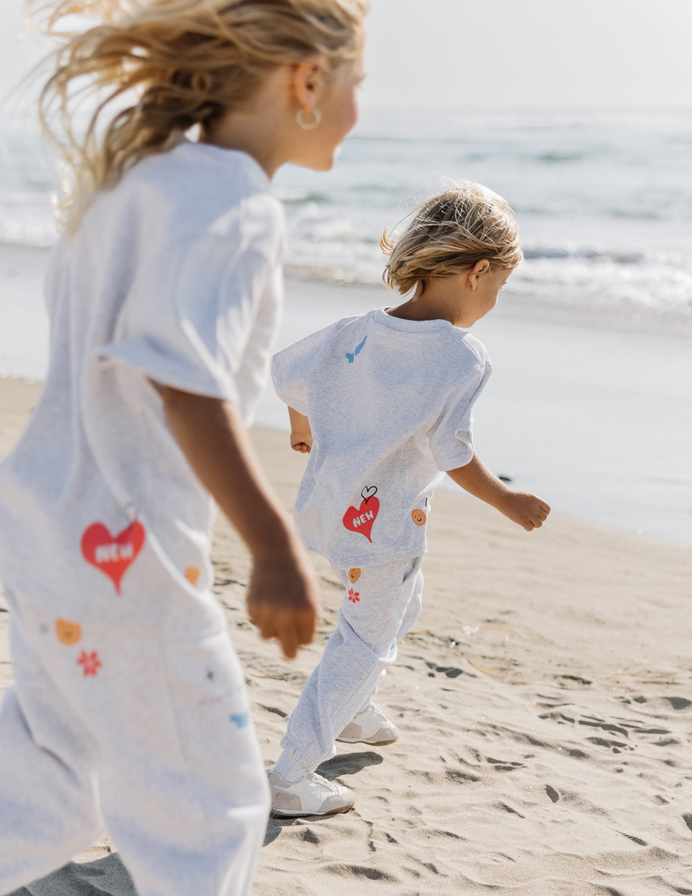 Two children wearing Elevated Faith Kids T-Shirt, perfect for Christian Kids Apparel, running on the beach
