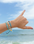 Elevated Faith Christian Jewelry Bracelet in a colorful string design worn on a beach hand gesture
