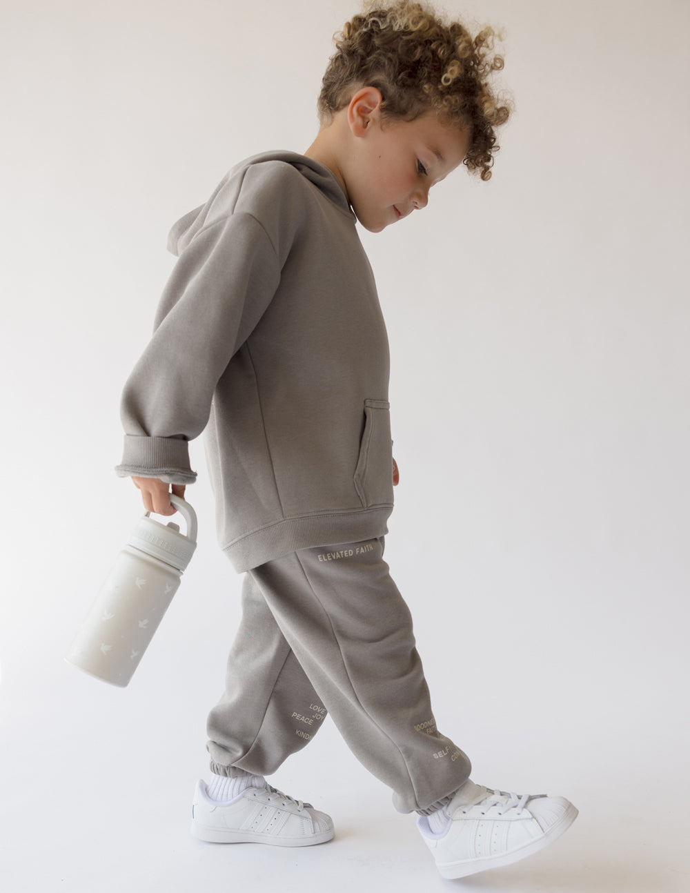 Kid carrying Elevated Faith Kids Water Bottle while wearing Christian Kids Apparel in gray outfit