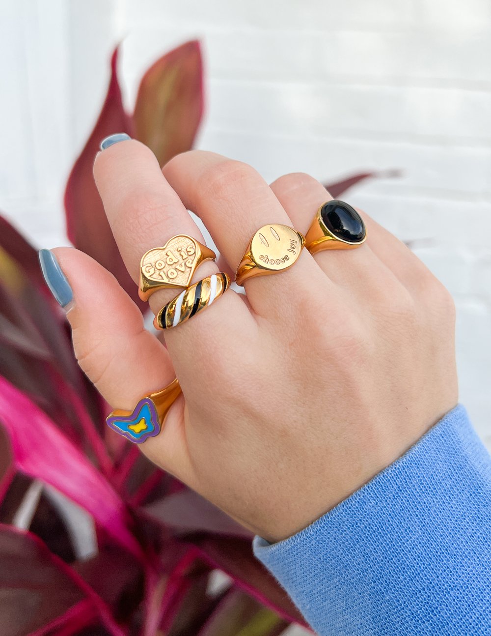 Christian Jewelry rings showcased on a hand with colorful plants in the background