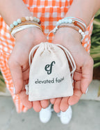 Elevated Faith Christian Bracelet in hand with a drawstring pouch for faith-inspired accessories