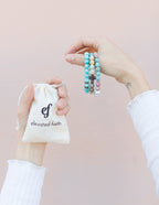 Woman holding stone bracelets from Elevated Faith in a drawstring bag, perfect Christian Jewelry Bracelet