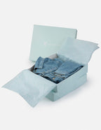 Elevated Faith packaging featuring a folded denim jacket and tissue paper for Christian Apparel