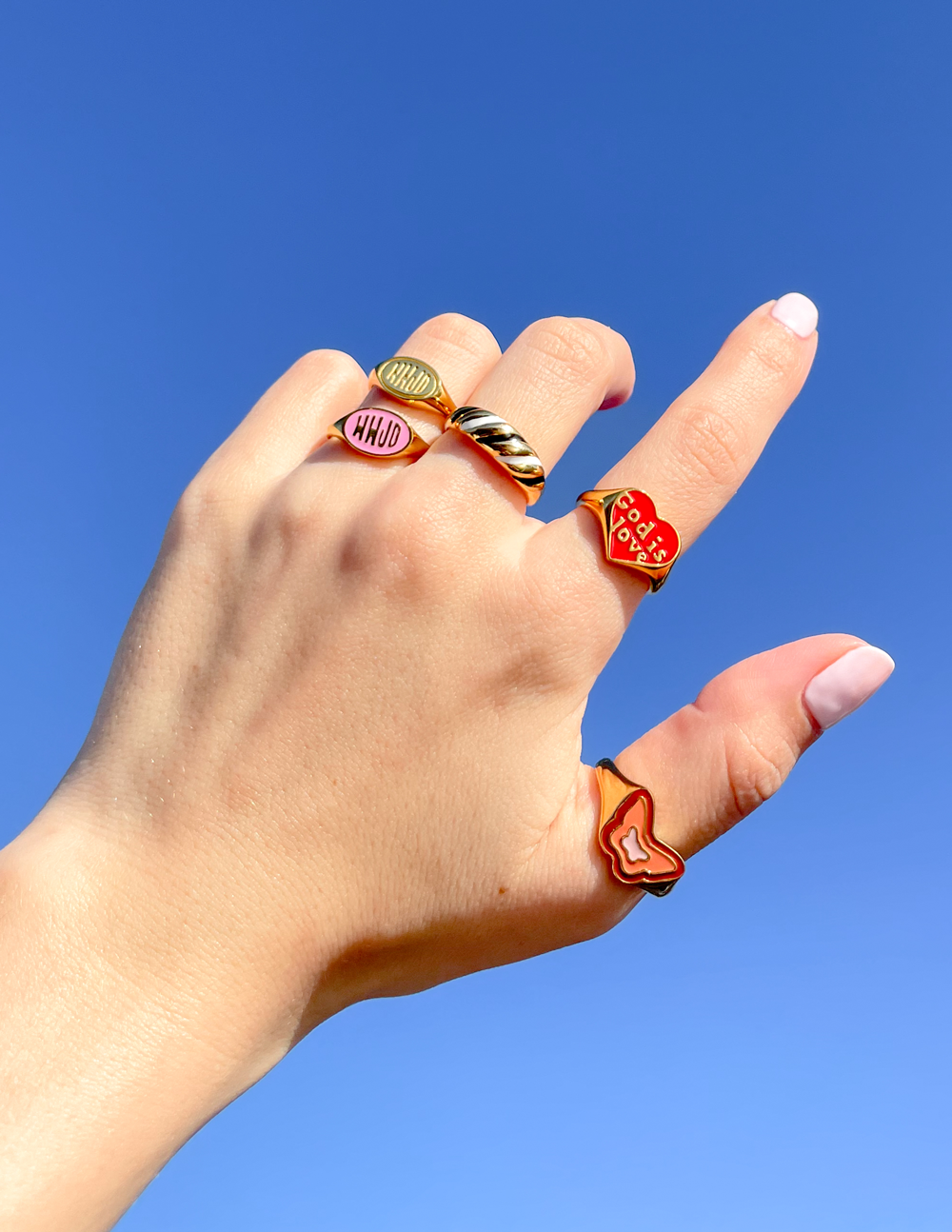 Colorful rings on hand showcasing Elevated Faith designs, perfect for Christian Jewelry lovers.